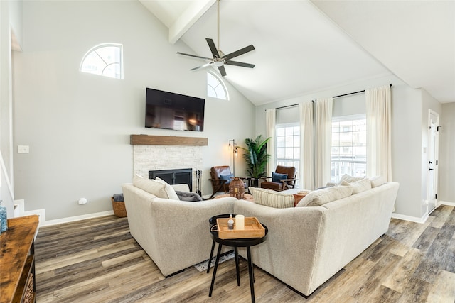 living room featuring beam ceiling, ceiling fan, a stone fireplace, high vaulted ceiling, and hardwood / wood-style floors