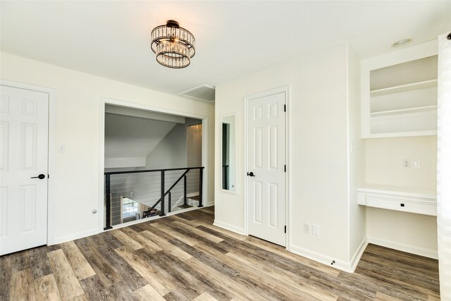 empty room featuring wood-type flooring and a notable chandelier