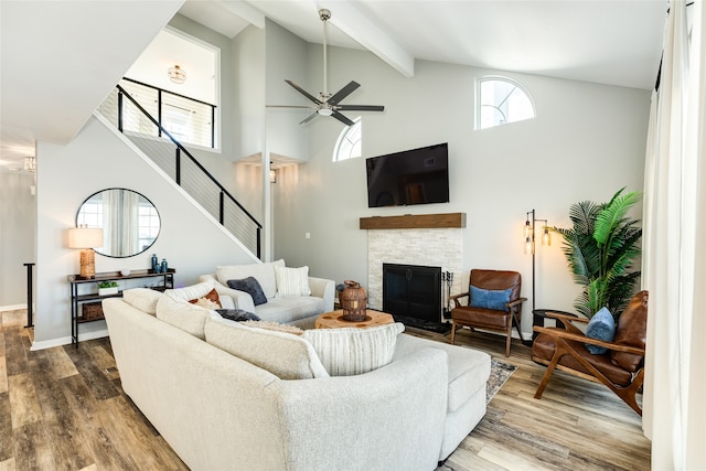 living room featuring ceiling fan, high vaulted ceiling, beamed ceiling, hardwood / wood-style floors, and a fireplace