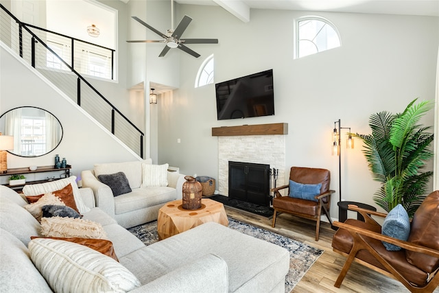 living room with high vaulted ceiling, ceiling fan, a fireplace, beamed ceiling, and wood-type flooring