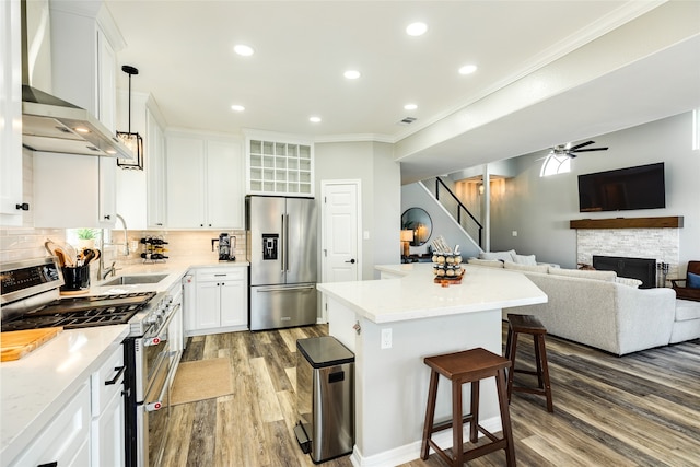 kitchen featuring sink, a center island, wall chimney exhaust hood, white cabinets, and appliances with stainless steel finishes