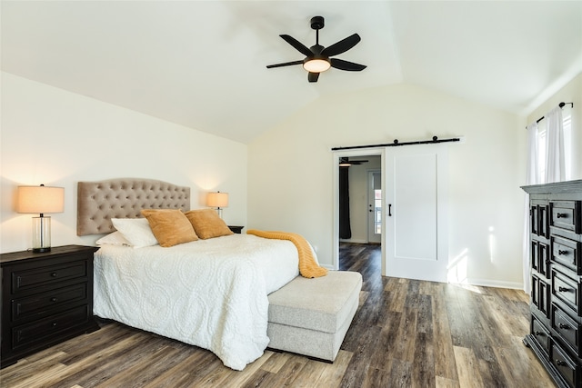 bedroom with dark hardwood / wood-style floors, a barn door, ceiling fan, and vaulted ceiling