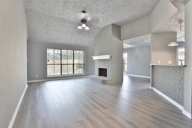 unfurnished living room with ceiling fan, a fireplace, wood-type flooring, and vaulted ceiling