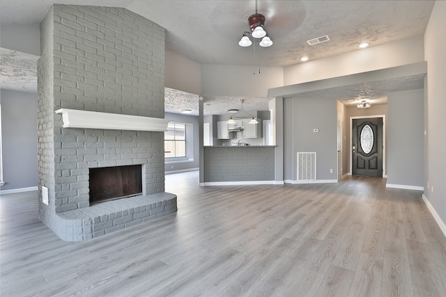 unfurnished living room featuring ceiling fan, a textured ceiling, and light hardwood / wood-style flooring