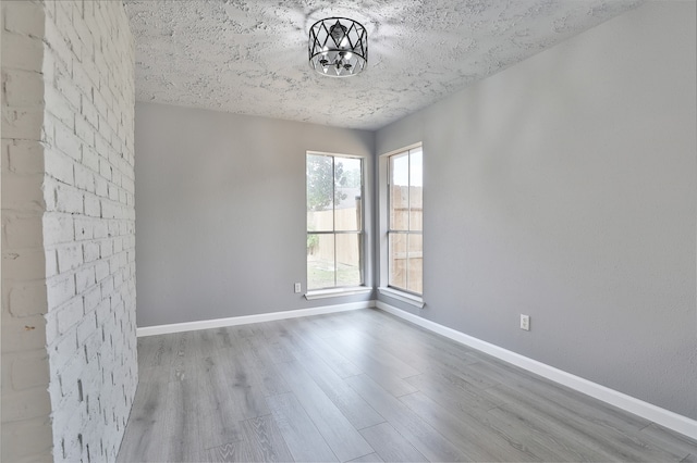 spare room featuring hardwood / wood-style flooring, a notable chandelier, and a textured ceiling