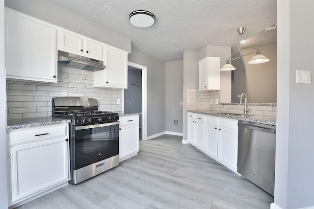 kitchen featuring sink, hanging light fixtures, light wood-type flooring, appliances with stainless steel finishes, and white cabinetry