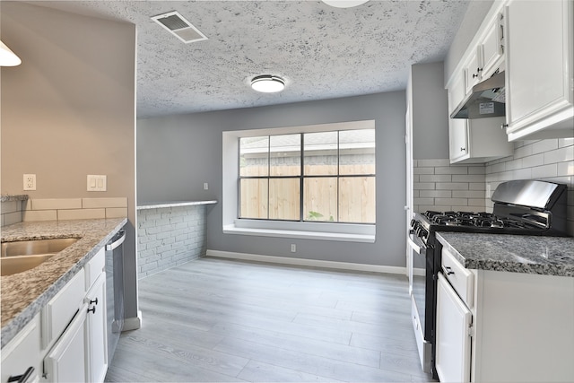 kitchen featuring sink, range with gas stovetop, a textured ceiling, stone countertops, and white cabinets