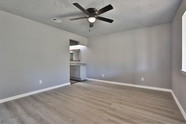 empty room featuring ceiling fan, a textured ceiling, and light hardwood / wood-style flooring