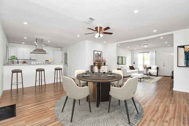 dining room featuring light wood-type flooring, a textured ceiling, and ceiling fan