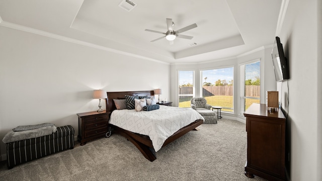 carpeted bedroom featuring a raised ceiling, ceiling fan, and ornamental molding