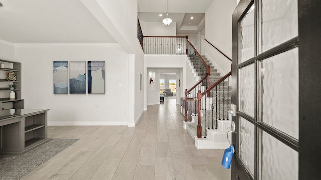 foyer with crown molding, light hardwood / wood-style flooring, and a high ceiling