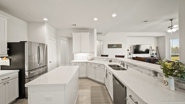 kitchen with white cabinetry, sink, stainless steel appliances, backsplash, and a kitchen island