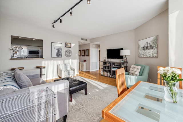 living room with light hardwood / wood-style floors and rail lighting