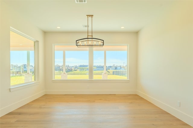 unfurnished dining area with light wood-type flooring and an inviting chandelier