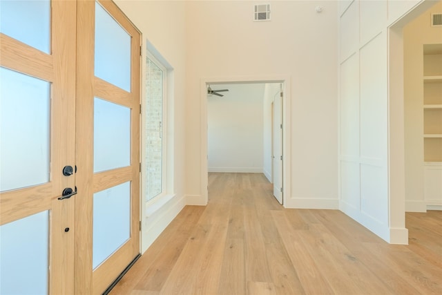 hall with built in shelves and light wood-type flooring