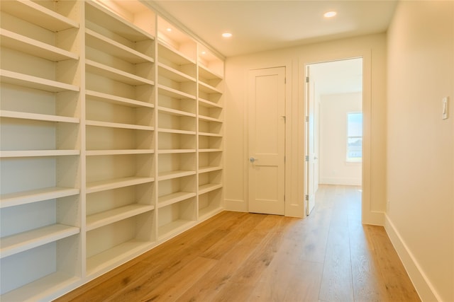 hallway with built in shelves and light hardwood / wood-style flooring