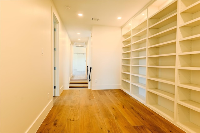 corridor with hardwood / wood-style flooring and built in shelves