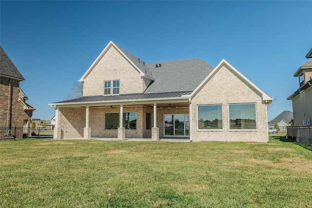 back of property with ceiling fan and a yard