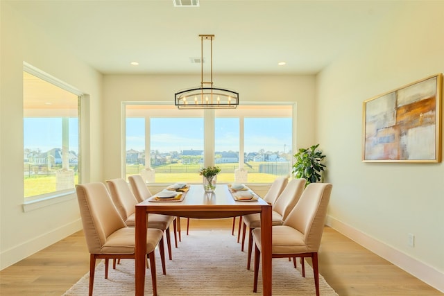 dining space with light hardwood / wood-style floors and a chandelier