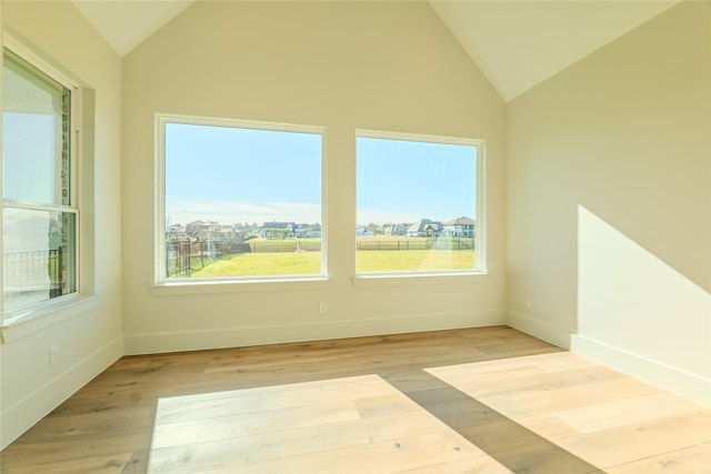 unfurnished room with light wood-type flooring and vaulted ceiling