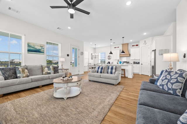 living room with a wealth of natural light, light hardwood / wood-style flooring, and ceiling fan