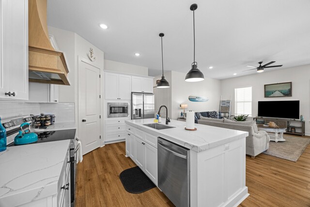 kitchen featuring stainless steel appliances, sink, a kitchen island with sink, and white cabinets