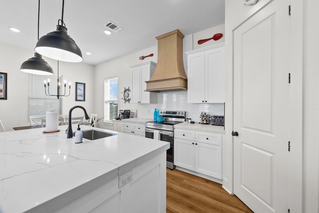 kitchen featuring white cabinetry, custom range hood, stainless steel range with electric cooktop, and decorative light fixtures