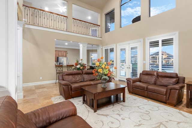 living room featuring decorative columns, ceiling fan, a high ceiling, and ornamental molding