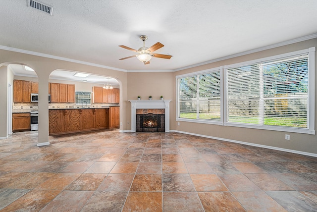 unfurnished living room with a tile fireplace, a textured ceiling, ceiling fan, and ornamental molding