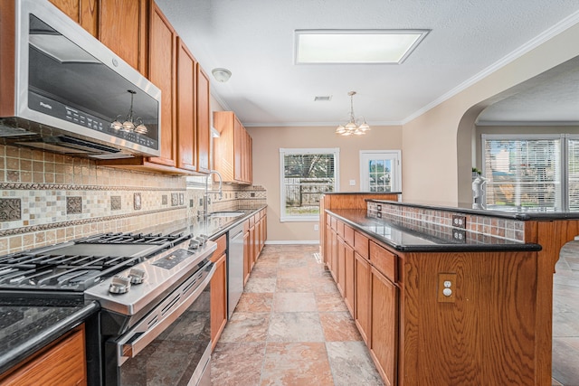 kitchen featuring backsplash, sink, a notable chandelier, a kitchen island, and stainless steel appliances