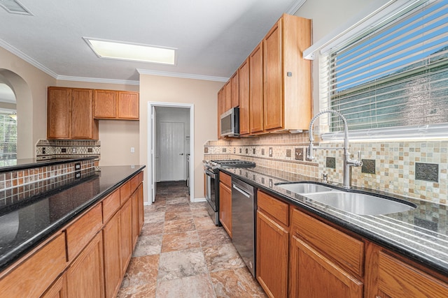 kitchen with crown molding, sink, decorative backsplash, dark stone countertops, and appliances with stainless steel finishes