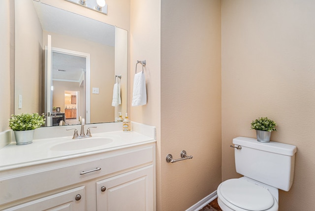 bathroom with toilet, vanity, and ornamental molding