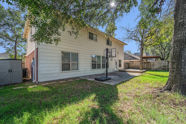 back of house with a storage shed, a patio area, and a lawn