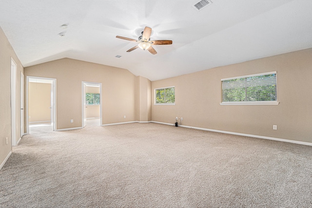 empty room featuring ceiling fan, lofted ceiling, and light carpet