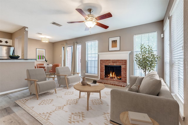 living room with plenty of natural light, ceiling fan, light wood-type flooring, and a fireplace