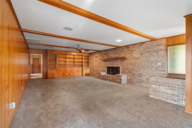 unfurnished living room with beam ceiling, wood walls, a fireplace, and carpet floors