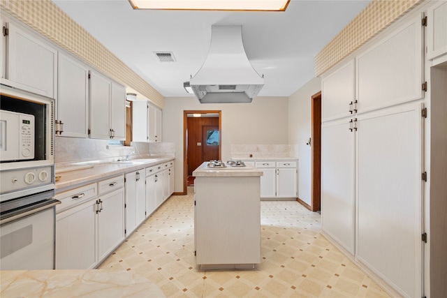 kitchen featuring wall oven, white cabinetry, and exhaust hood