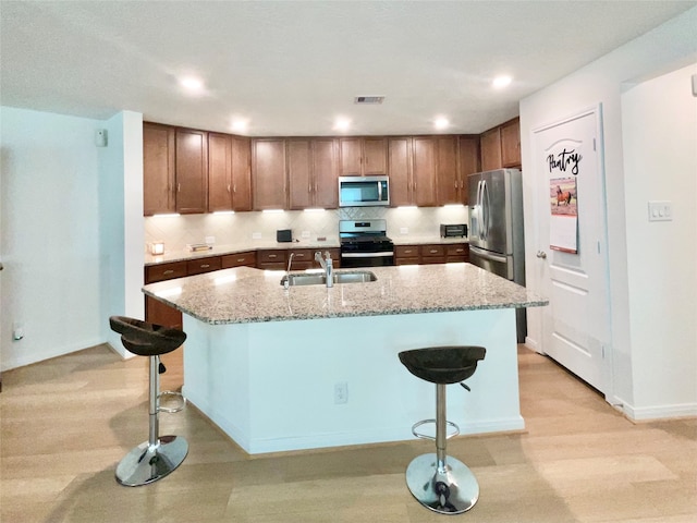 kitchen featuring a kitchen bar, a center island with sink, and appliances with stainless steel finishes