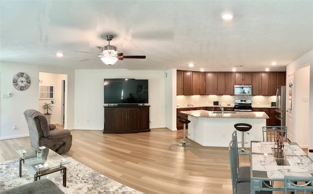 kitchen with a breakfast bar, light hardwood / wood-style floors, sink, and stainless steel appliances