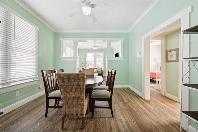 dining area featuring decorative columns, crown molding, ceiling fan, and wood-type flooring