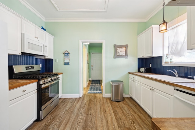 kitchen featuring white cabinetry, pendant lighting, white appliances, and light hardwood / wood-style floors