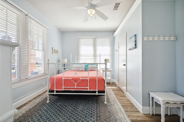 bedroom with ceiling fan, wood-type flooring, and a textured ceiling