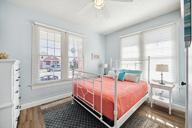 bedroom with ceiling fan, wood-type flooring, a textured ceiling, and multiple windows