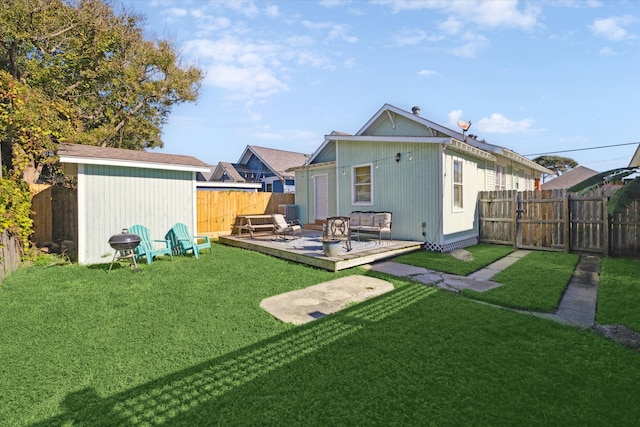 rear view of property featuring an outdoor hangout area, a deck, a storage shed, and a lawn