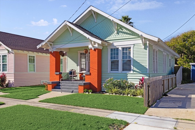 bungalow featuring covered porch and a front lawn