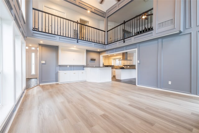 unfurnished living room with a towering ceiling and light hardwood / wood-style floors