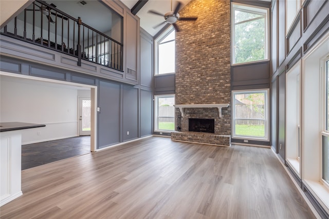 unfurnished living room featuring a fireplace, wood-type flooring, high vaulted ceiling, and plenty of natural light