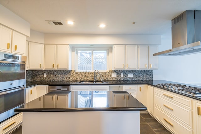 kitchen with a center island, wall chimney range hood, sink, appliances with stainless steel finishes, and white cabinetry