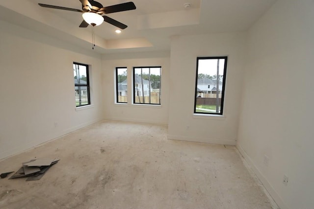 unfurnished room featuring a raised ceiling and ceiling fan