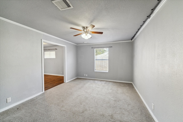 carpeted spare room featuring ceiling fan, ornamental molding, and a textured ceiling